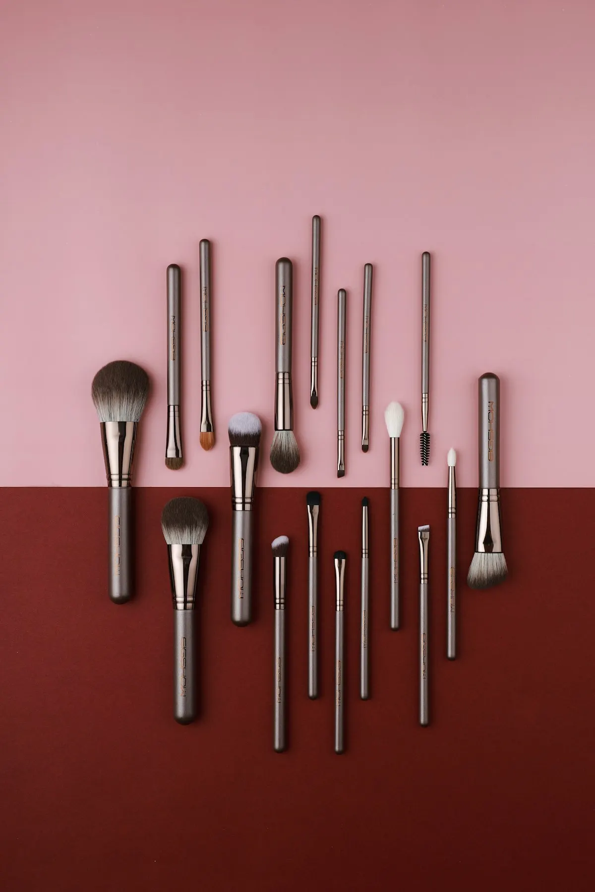 Make-up brushes laid out on a pink and burgundy background
