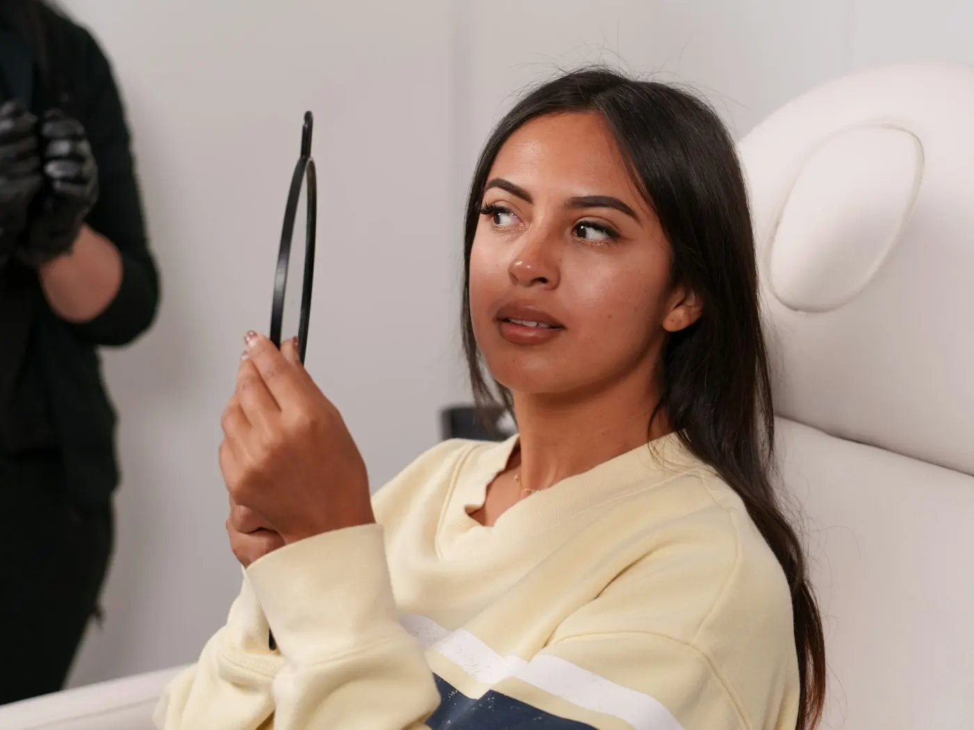 Client checking her results in a hand mirror after treatment