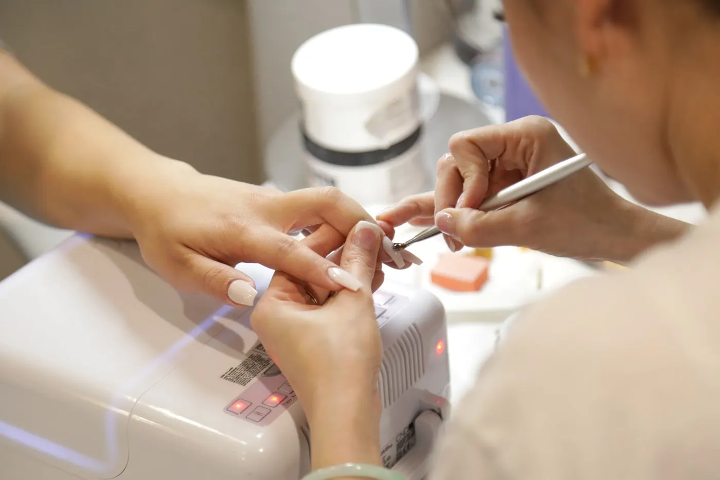 Nail technician painting a client's nails at the studio desk